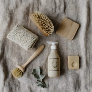 A flat lay of eco-friendly cleaning essentials, including a spray bottle, scrub brushes, a cloth, and a natural sprig. A flat lay of eco-friendly cleaning essentials, including a spray bottle, scrub brushes, a cloth, and a natural sprig.